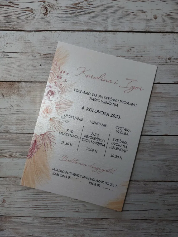 Pozivnica za vjenčanje na bijelom sjajnom papiru i ružičastim i bijelim cvijećem.