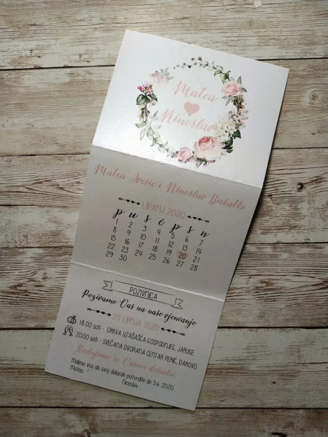 Pozivnice za vjenčanje s ružičastim ružama i imenima mladenaca u sredini.