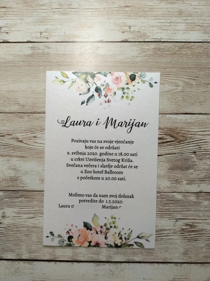 Pozivnica za vjenčanje na bijelom papiru i cvijećem šarenim na vrhu i na dnu.