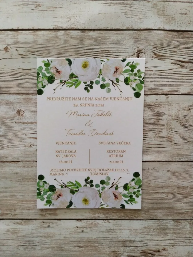 Pozivnica za vjenčanje s bijelim cvijećem i zelenim lišćem.