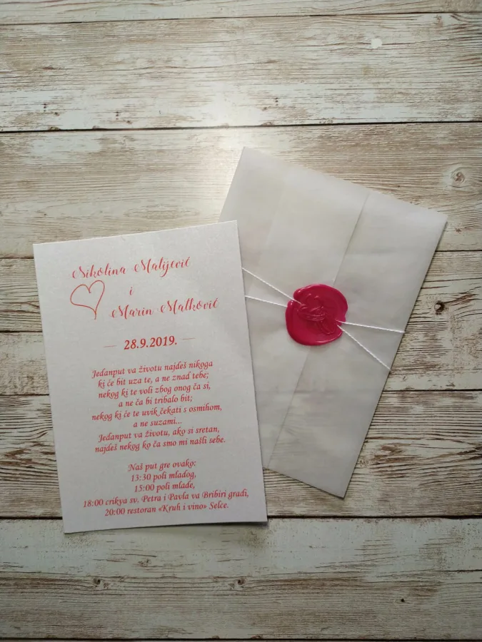 Pozivnica za vjenčanje s crvenim fontom, omotom i crvenim pečatom.