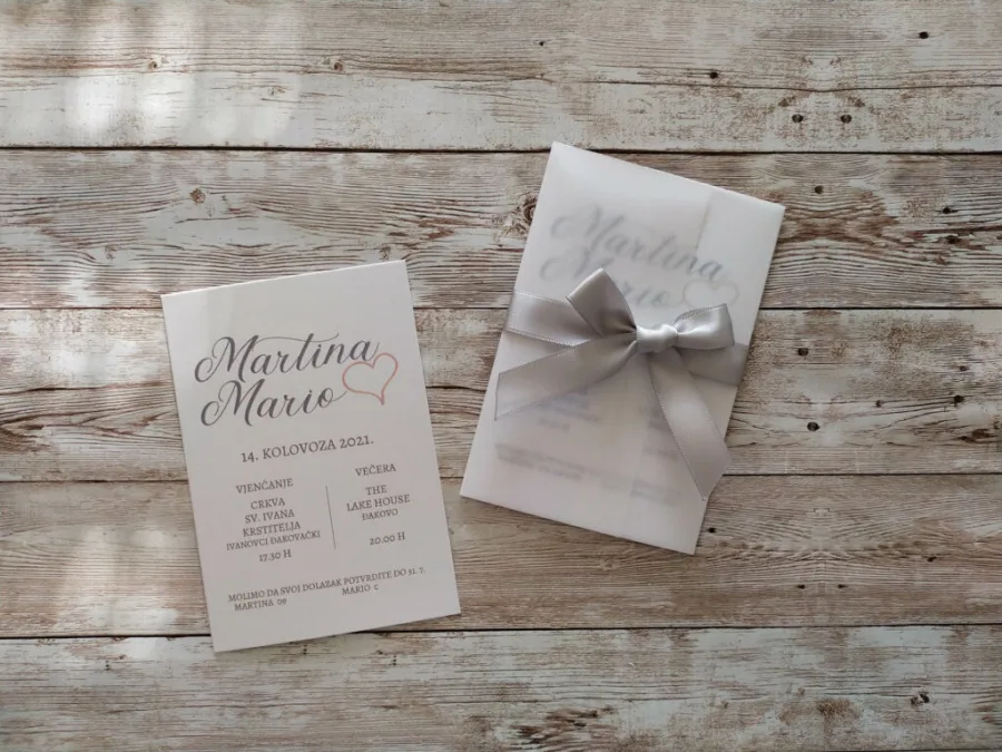 Pozivnica za vjenčanje s srebrenom mašnom i omotom od zamagljenog papira.