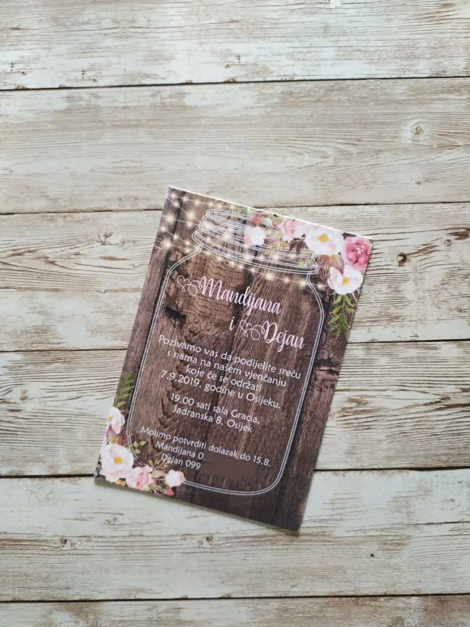 Pozivnica za vjenčanje brenda Papirusha koja izgleda kao fotografija drveta smeđeg, ukrašena bijelo-ružičastim cvijećem i lampicama na vrhu.