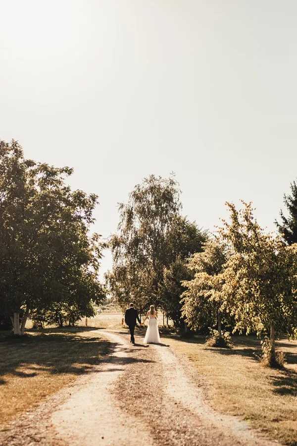 Mladoženja i mlada se drže za ruku u prirodi.