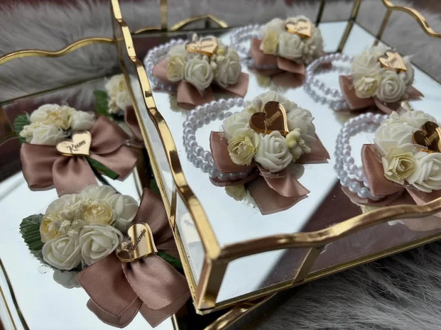 Krem ružičaste narukvice s bijelim ružama na ogledalu.