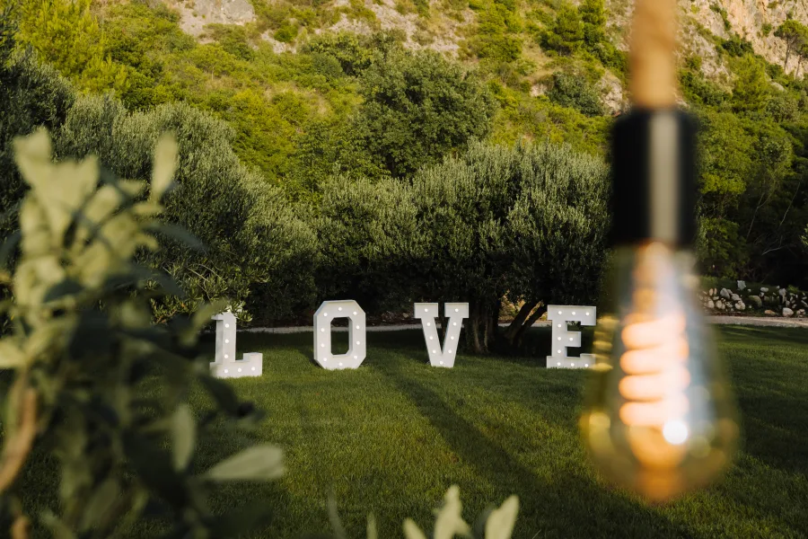 Natpis LOVE samostojeća slova na travnjaku ispred maslina.