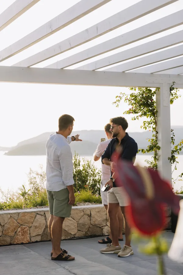 Osobe na terasi pričaju i gledaju u more.