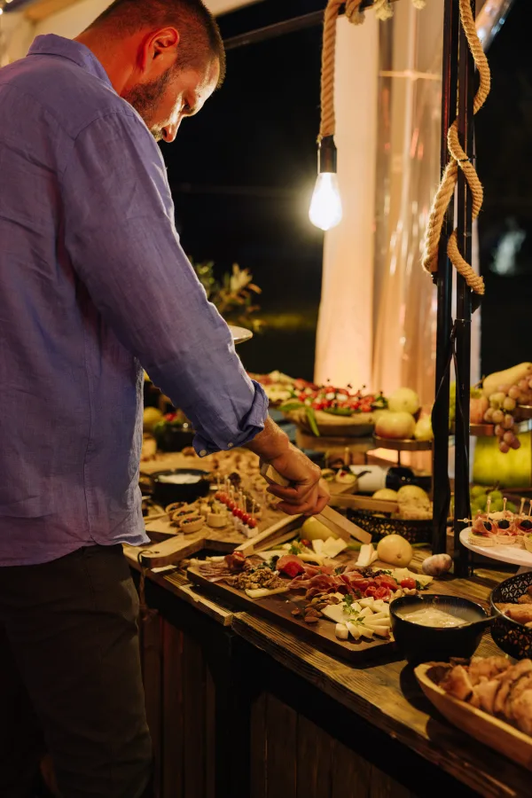 Gost vjenčanja uzima hladna predjela i nareske s drvenog stola.