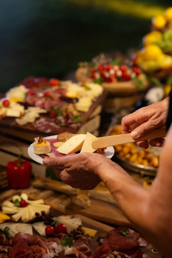Gost vjenčanja stavlja hladna predjela i nareske u tanjur u sali za vjenčanje.