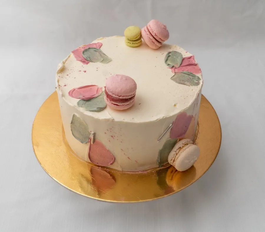 Bijela torta sa pastelnim rozim i zelenim bojama.