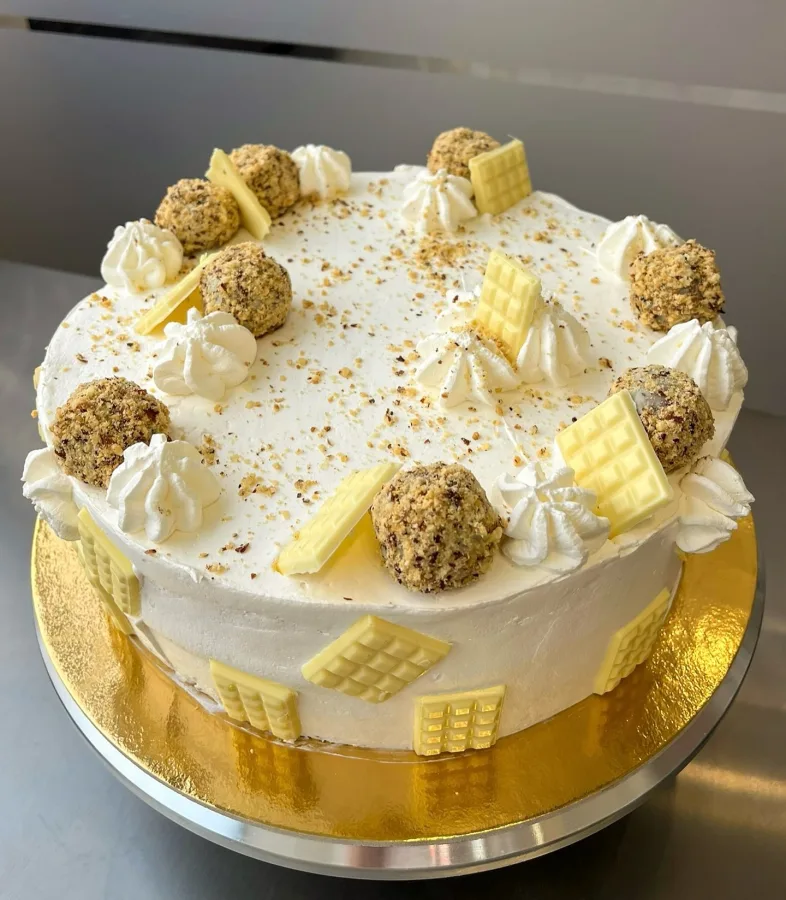 Bijela torta s malim bijelim čokoladicama i okruglicama.