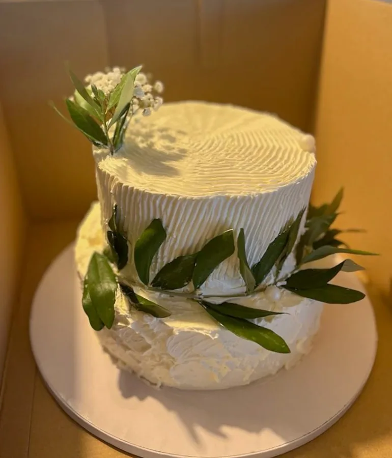 Bijela torta na dva kata sa zelenim listovima.