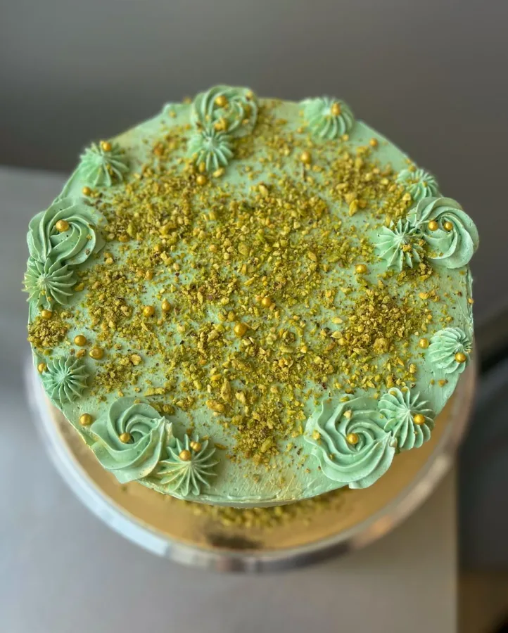 Zelena torta posuta pistacijem i zlatnim kuglicama.