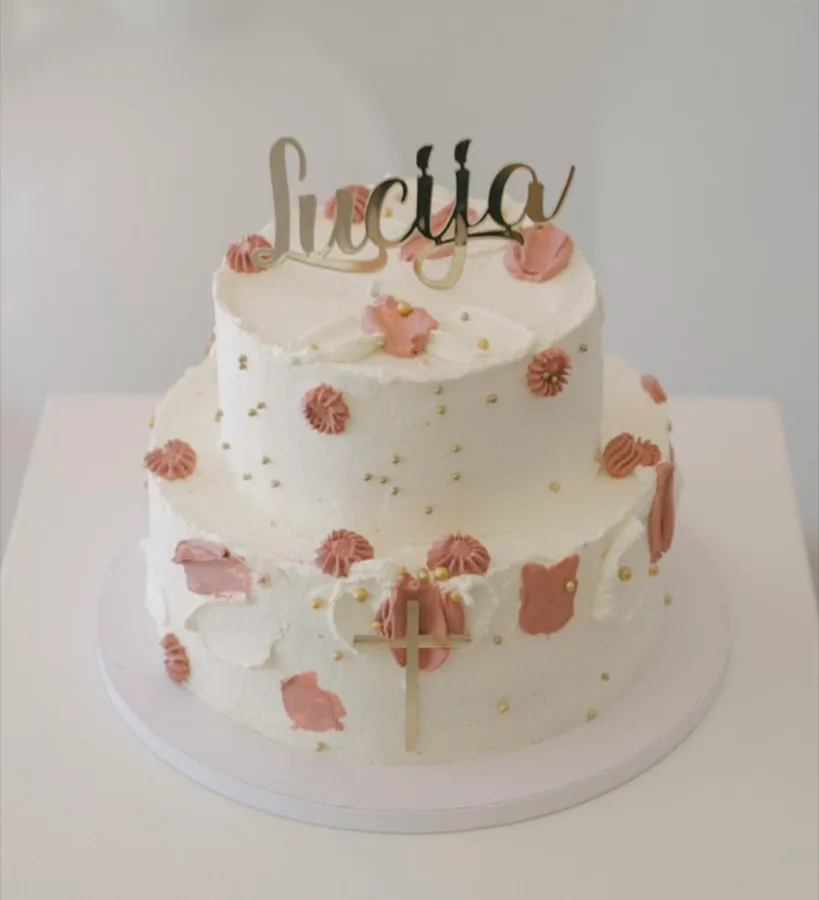 Bijela torta s pastelno rozim cvjetovima za krštenje s natpisom Lucija.