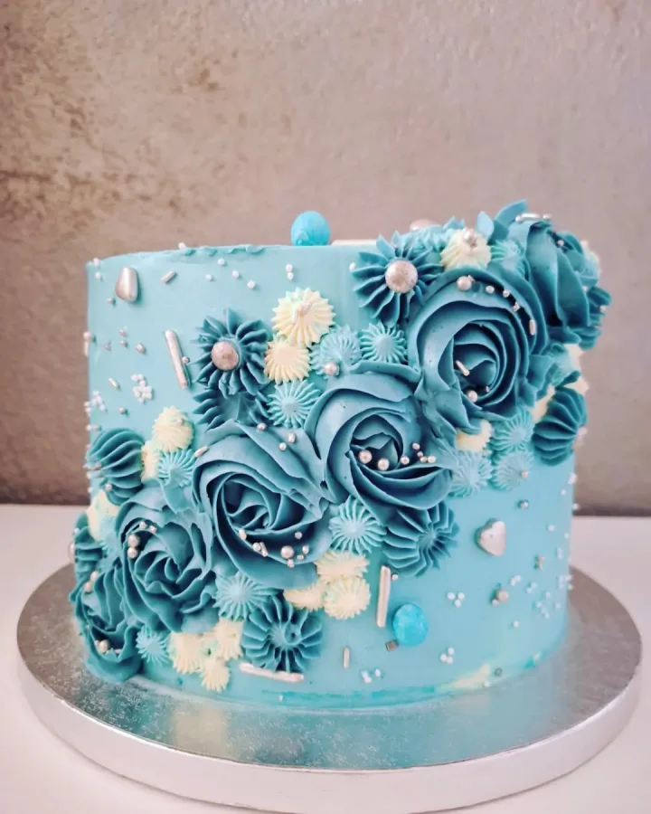 Plava torta s plavim ružama i bijelim cvijeće od kreme.
