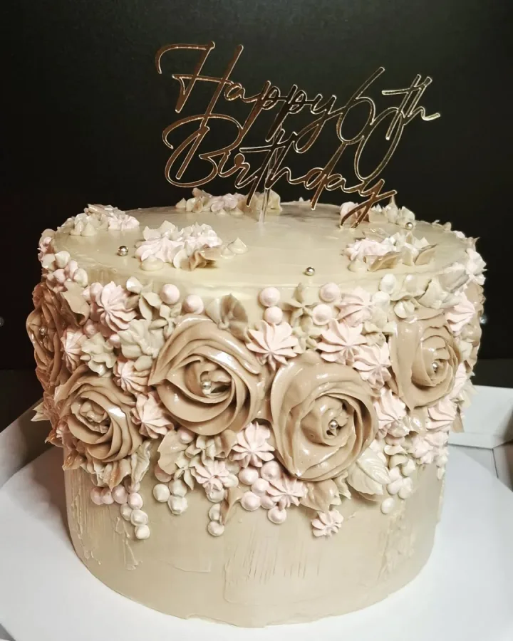 Svjetlo smeđa torta s ružicama od kreme i natpisom "Happy 6th Birthday".
