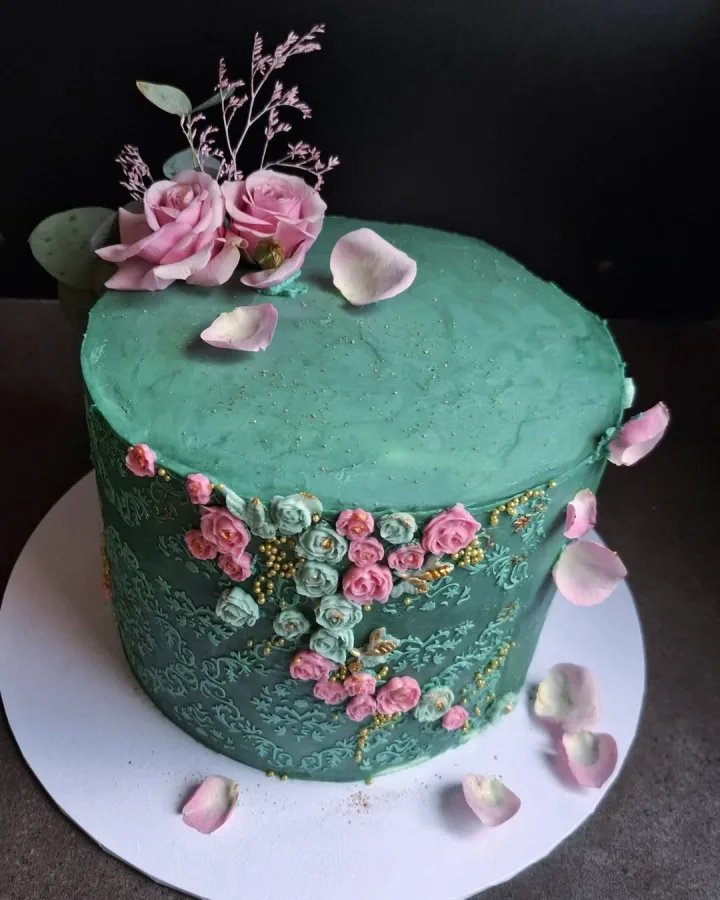Zelena torta ukrašena zelenim i ružičastim cvijećem i pravim ružičastim ružama.