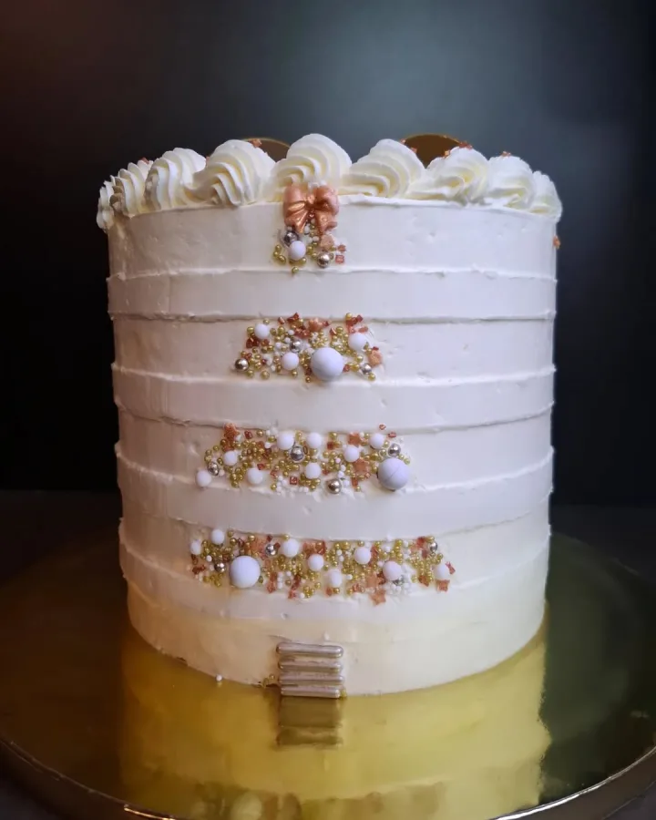 Bijela torta ukrašena jestivim perlicama u obliku božićnog drvca,