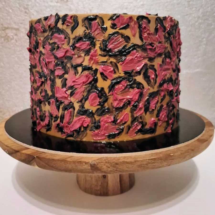 Smećkasta torta s crvenkastim mrljama od kreme i crnim obrubom oko mrlja od kreme.