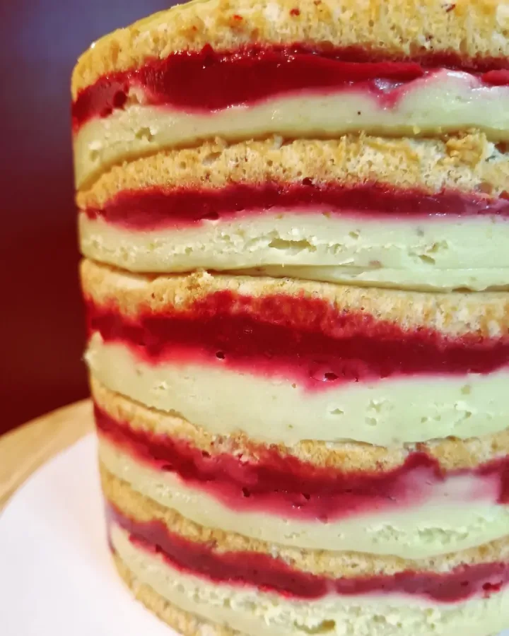 Presjek torte s kremama od pistacija i višnje.