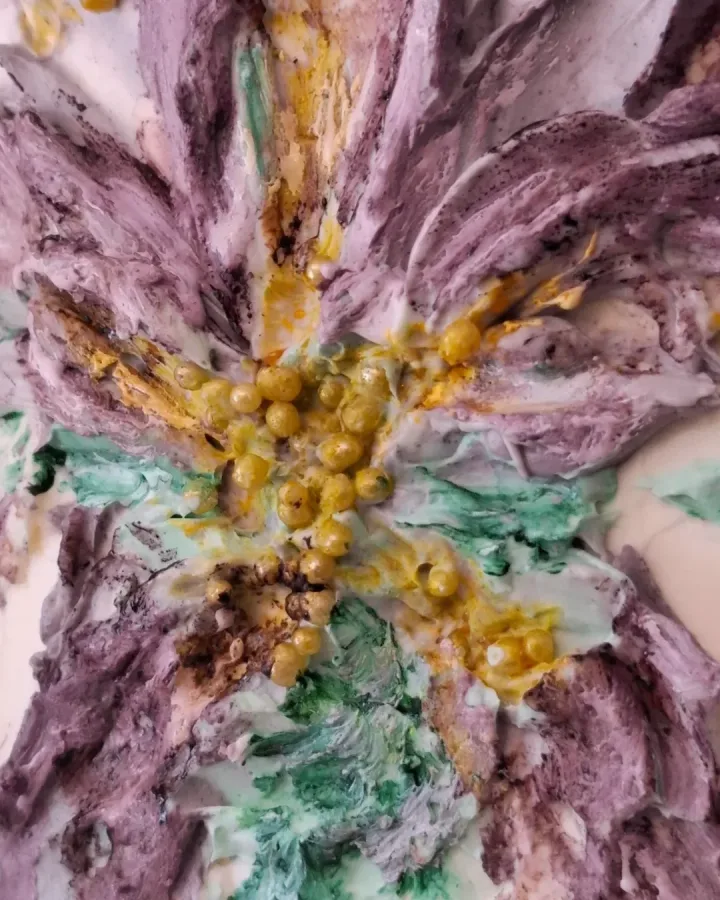 Ukras cvijeta na torte od kreme zelene i ljubičaste boje s žutim perlicama kao tučak.