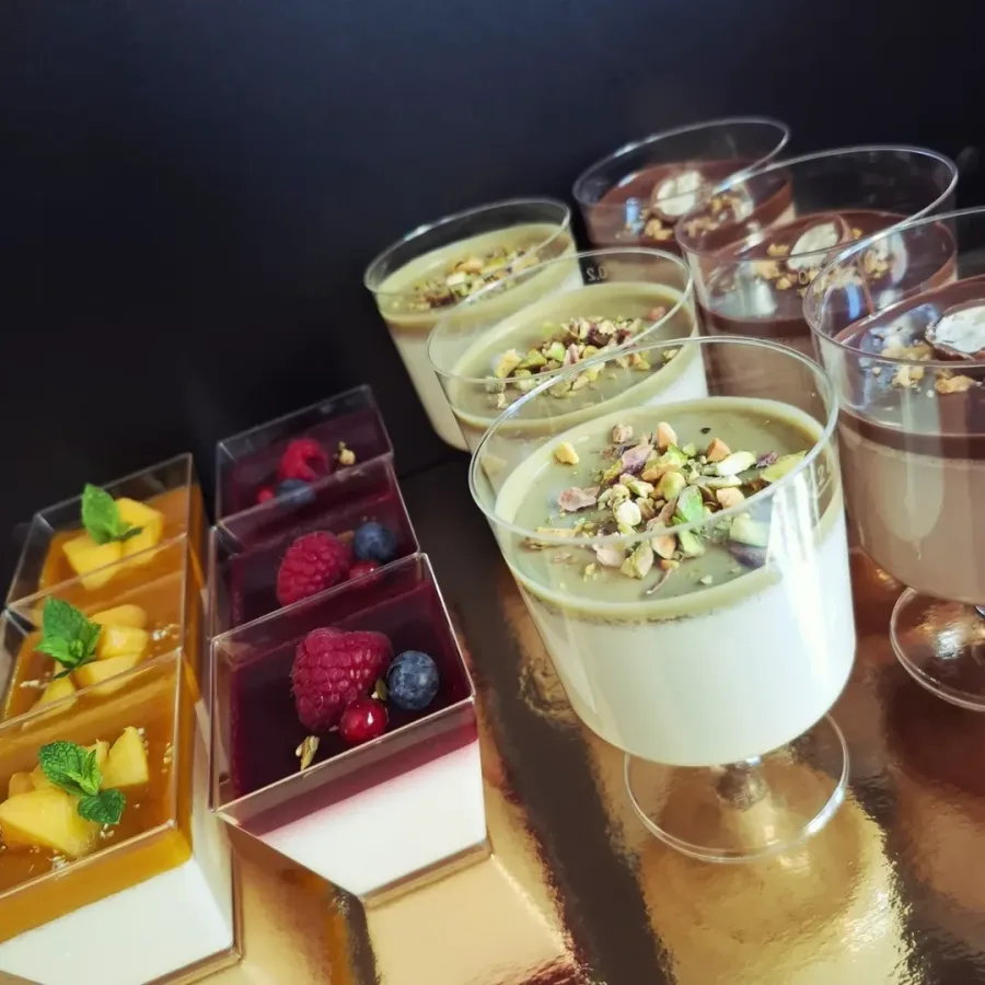 Panna cotta u čašicama s preljevima od šumskog voća, čokolade, pistacija i manga za vjenčanja i ostale proslave.