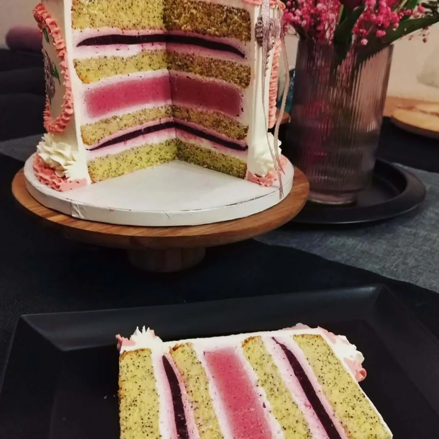 Presjek torte s biskvitom od maka, želeom od šumskog voća, kremom od vanilije i kremom od malina.
