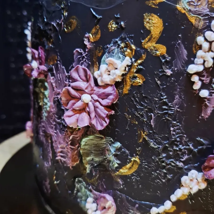 Tamna torta s raznim šarenim cvijećem od kreme.