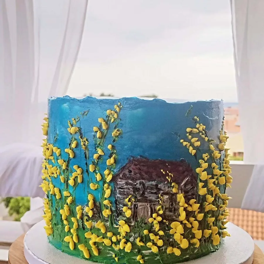 Torta s zelenom kremom koja prikazuje travu, plavom koja prikazuje nebo, žutom koja prikazuje cvijeće i smeđom koja prikazuje kuću.