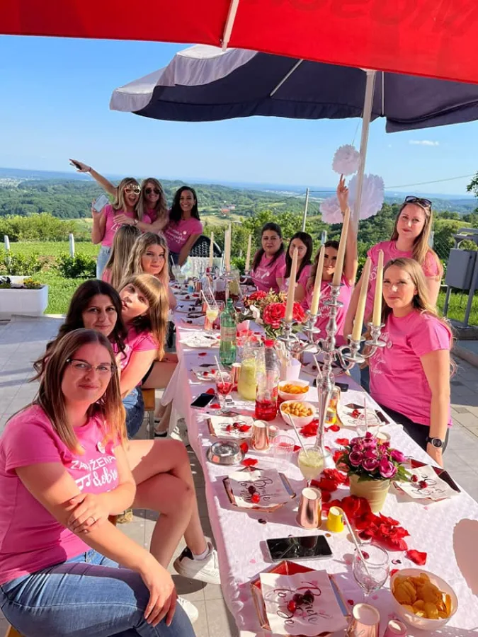 Djevojčka u vili za vjenčanje. Djevojke nose ružičaste majice kratkih rukava i sjede za stolom s hranom u vrtu vile.