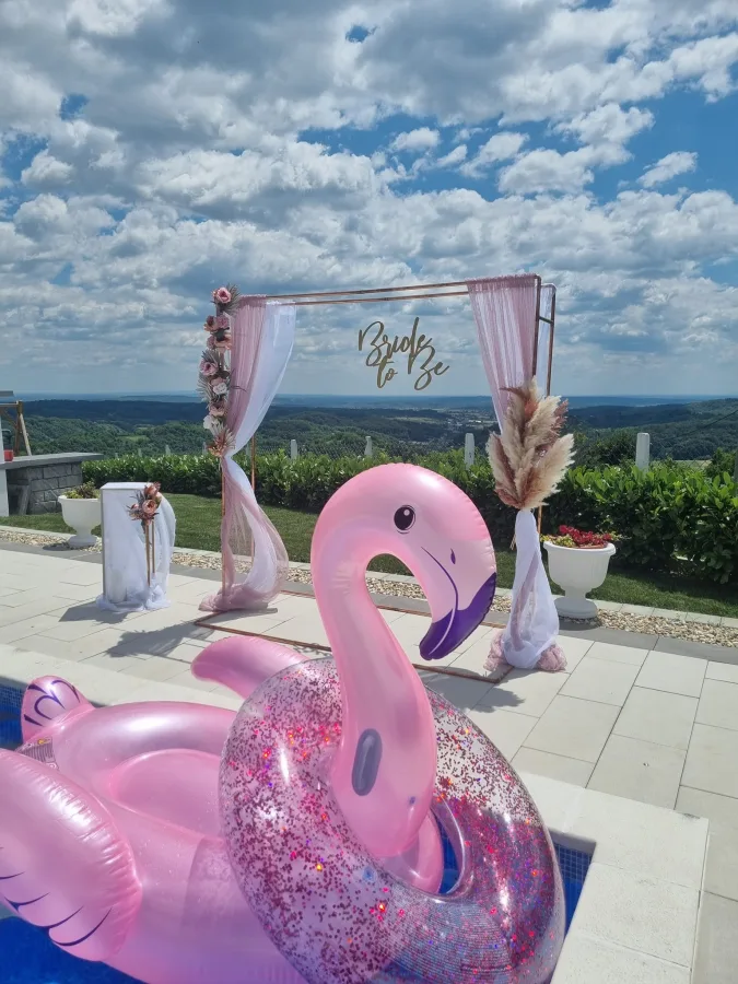 Dekoracija za djevojačku s natpisom "Bride to be" pokraj bazena vile za vjenčanja. U bazeni je ružičasti napuhanac flamingo i kolut sa šljokicama.