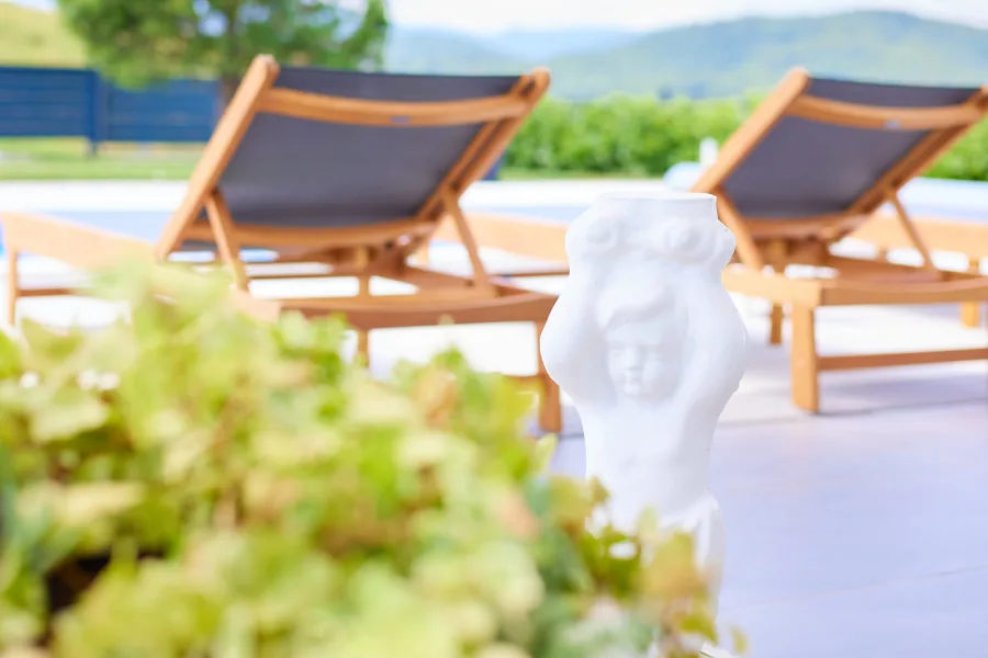 Bijela vrtna skulptura djeteta pokraj dvije ležaljke u vrtu vile za vjenčanja pokraj Zagreba.