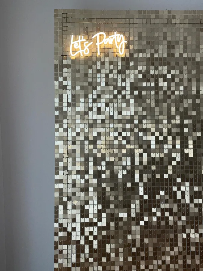 Metalik srebren zid s neonskim natpisom 'let's party', idealan za fotografiranje na vjenčanju.