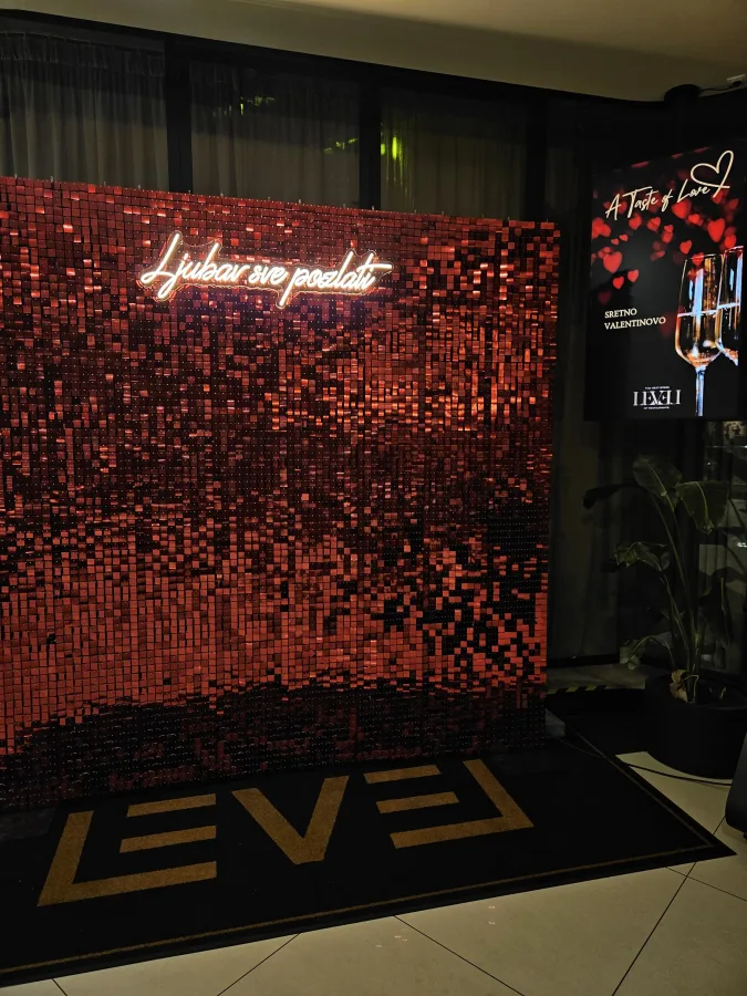 Metalik crven zid s neonskim natpisom 'ljubav sve pozlati', idealan za fotografiranje na vjenčanju.