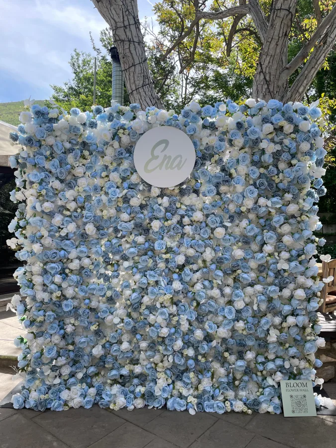Zid s bijelim i plavim ružama i natpisom Ena, idealan za fotografiranje na proslavi.