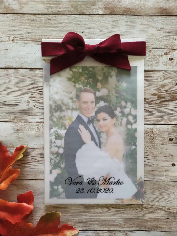Fotografija mladenaca kao zahvalnica za vjenčanje s crvenom mašnom na vrhu fotografije.